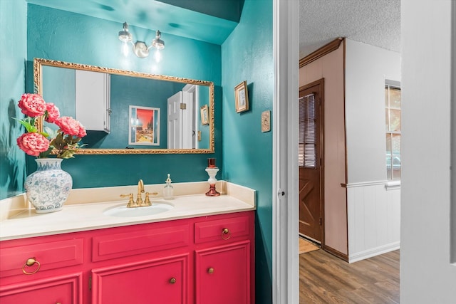 bathroom featuring vanity, ornamental molding, hardwood / wood-style floors, and a textured ceiling