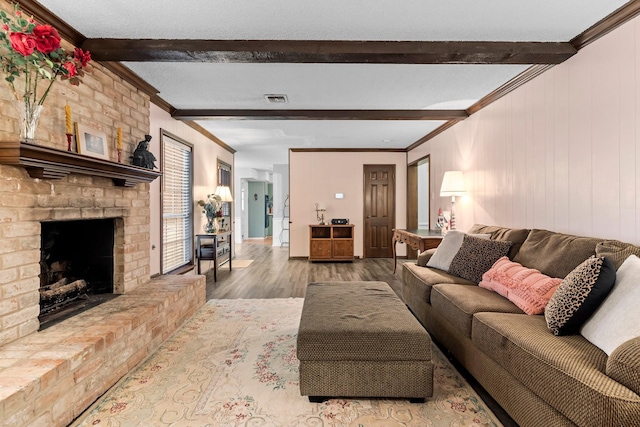 living room with hardwood / wood-style flooring, ornamental molding, a brick fireplace, and beam ceiling