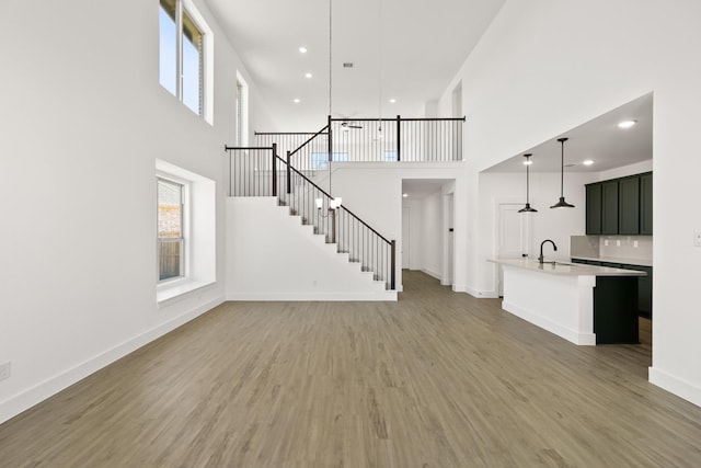 unfurnished living room featuring sink, dark wood-type flooring, and a high ceiling