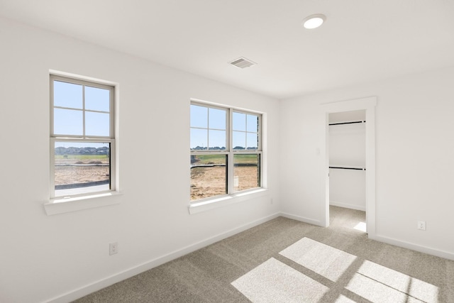 unfurnished bedroom with light carpet, a spacious closet, and a closet