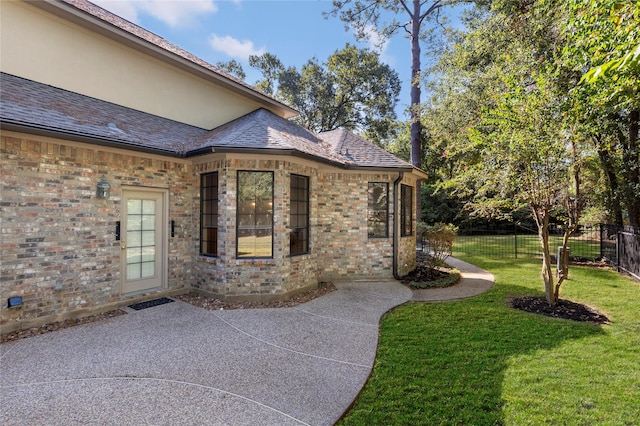 view of exterior entry with a yard and a patio area