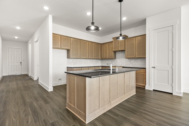 kitchen featuring sink, hanging light fixtures, dark hardwood / wood-style flooring, an island with sink, and decorative backsplash