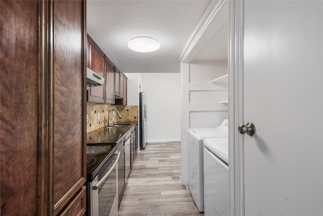 kitchen with washer and clothes dryer, appliances with stainless steel finishes, tasteful backsplash, extractor fan, and light wood-type flooring