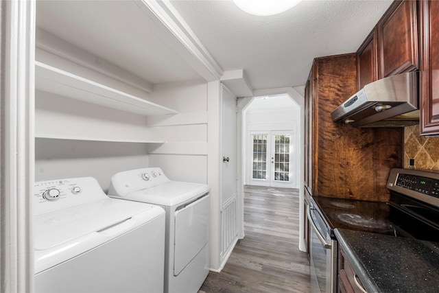 laundry area featuring wood-type flooring, crown molding, washing machine and clothes dryer, and a textured ceiling