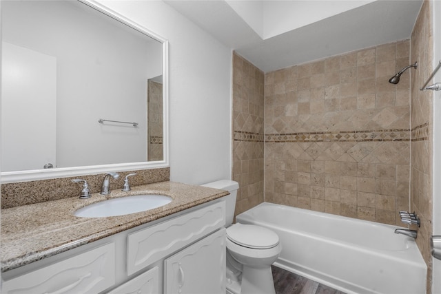 full bathroom featuring tiled shower / bath, hardwood / wood-style floors, vanity, and toilet