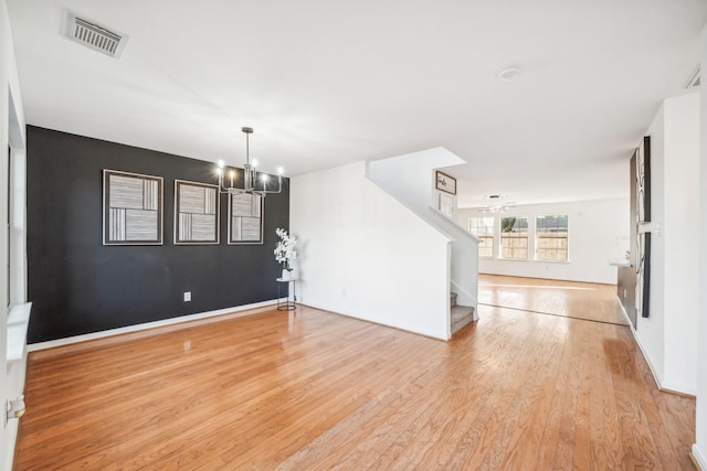 unfurnished living room with a chandelier and light wood-type flooring