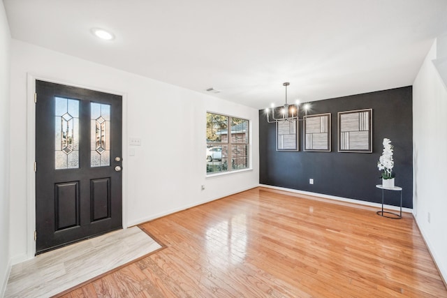 entryway with light hardwood / wood-style floors and a notable chandelier