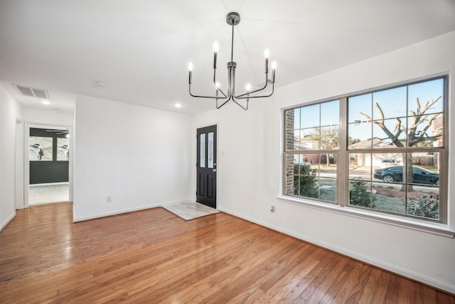 unfurnished dining area with a chandelier and light wood-type flooring