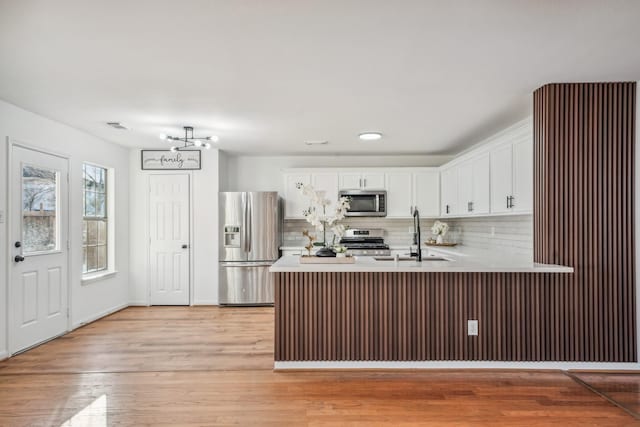 kitchen with stainless steel appliances, white cabinetry, sink, and kitchen peninsula