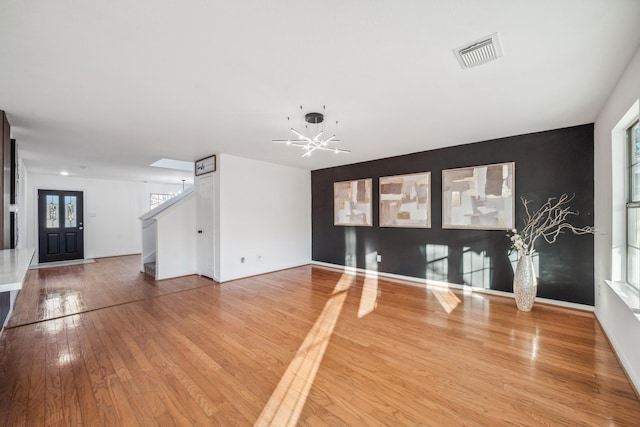 unfurnished living room with hardwood / wood-style flooring and a notable chandelier