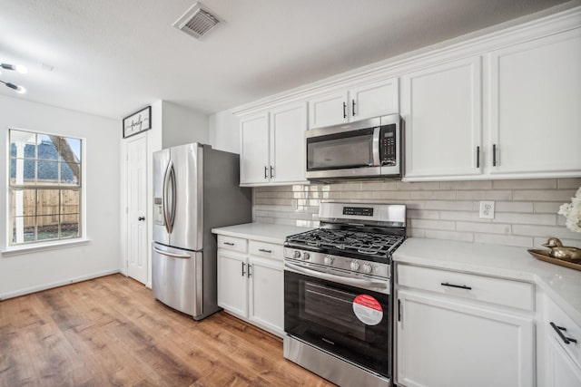 kitchen featuring tasteful backsplash, white cabinetry, appliances with stainless steel finishes, and light hardwood / wood-style floors