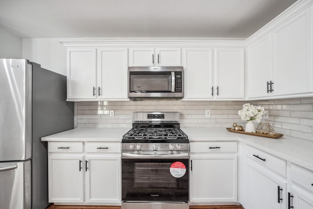 kitchen with decorative backsplash, white cabinets, and appliances with stainless steel finishes