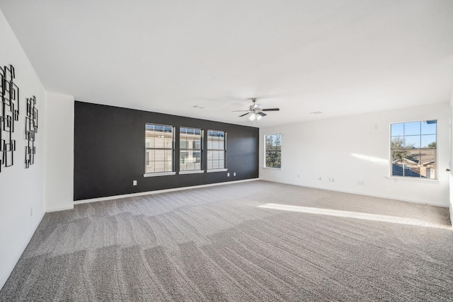 carpeted spare room featuring a wealth of natural light and ceiling fan