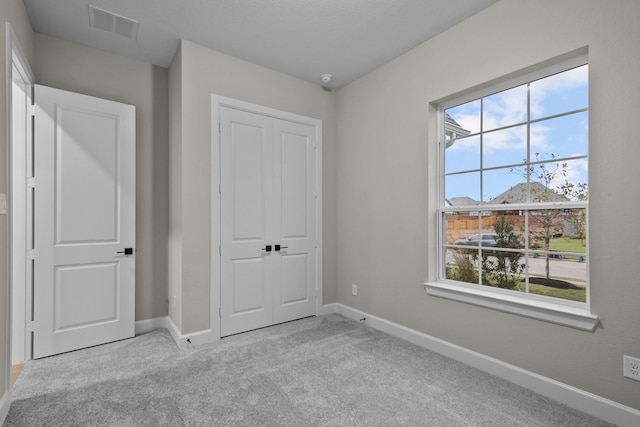 unfurnished bedroom with a closet and light carpet