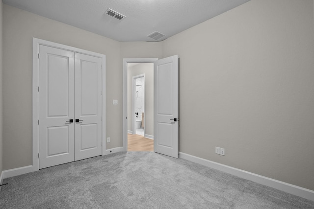 unfurnished bedroom with light carpet, a closet, and a textured ceiling