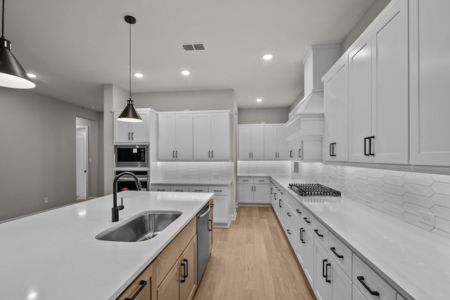 kitchen featuring hanging light fixtures, tasteful backsplash, sink, and white cabinets