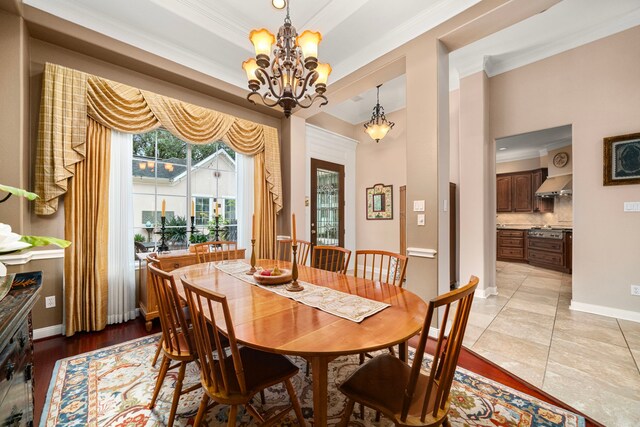 dining space featuring crown molding, a tray ceiling, a chandelier, and light tile patterned floors