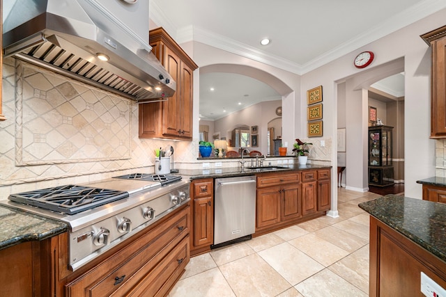 kitchen with wall chimney exhaust hood, sink, crown molding, dark stone counters, and stainless steel appliances