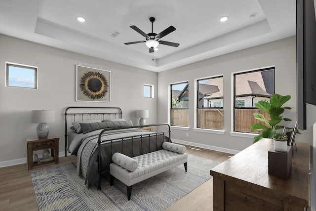 bedroom featuring hardwood / wood-style flooring, ceiling fan, and a tray ceiling