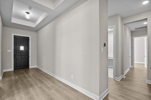 foyer entrance featuring a tray ceiling and light hardwood / wood-style flooring