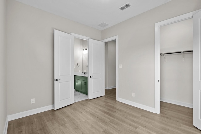 unfurnished bedroom with ensuite bathroom, sink, light hardwood / wood-style floors, and a closet