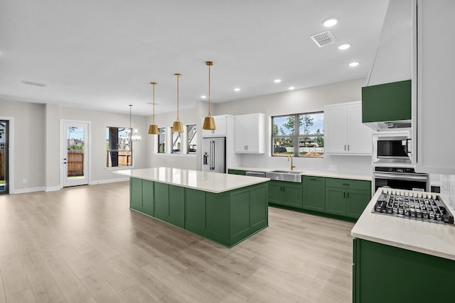 kitchen featuring appliances with stainless steel finishes, a center island, white cabinets, and green cabinetry