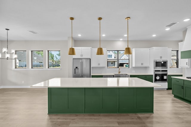 kitchen with a large island, sink, pendant lighting, appliances with stainless steel finishes, and white cabinetry