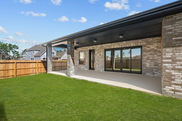 rear view of house with french doors, a patio, and a lawn