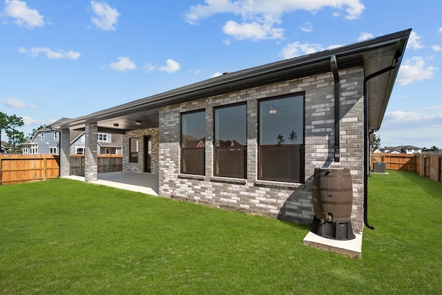 rear view of house with central AC, a patio area, and a lawn