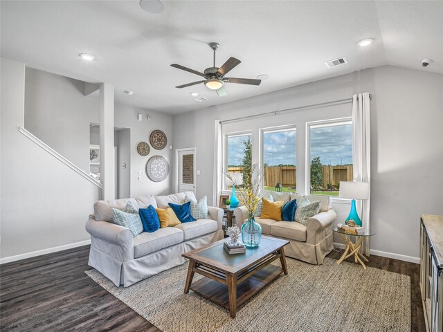 living area featuring visible vents, dark wood-type flooring, a ceiling fan, vaulted ceiling, and baseboards