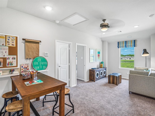 carpeted office space featuring attic access, visible vents, ceiling fan, and baseboards