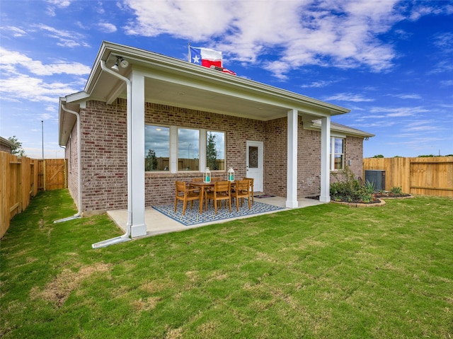 back of property featuring a yard, a fenced backyard, a patio, and brick siding