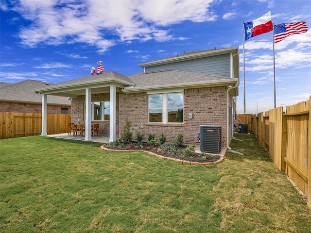 back of house with brick siding, a lawn, a patio area, cooling unit, and a fenced backyard