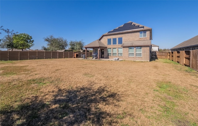 back of house with a patio area, solar panels, and a lawn