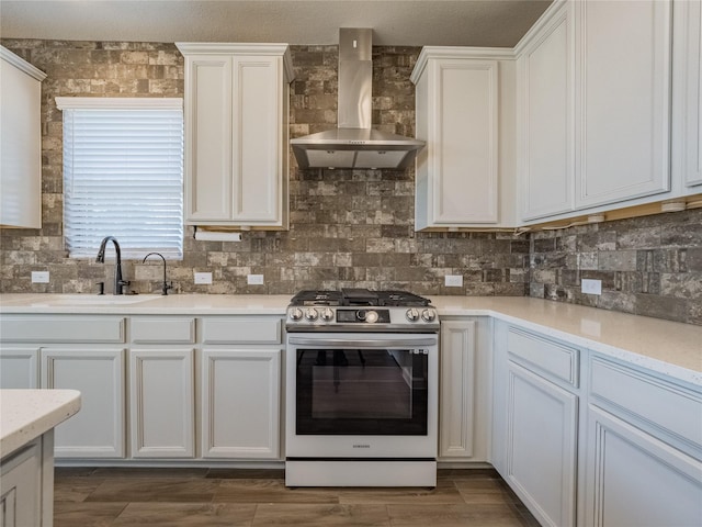 kitchen featuring sink, white cabinets, backsplash, gas stove, and wall chimney exhaust hood