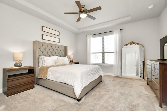 carpeted bedroom with ceiling fan and a tray ceiling