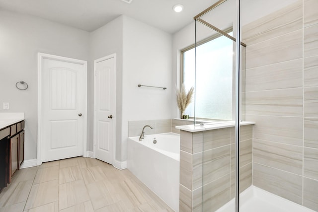 bathroom featuring tile patterned flooring, plus walk in shower, plenty of natural light, and vanity