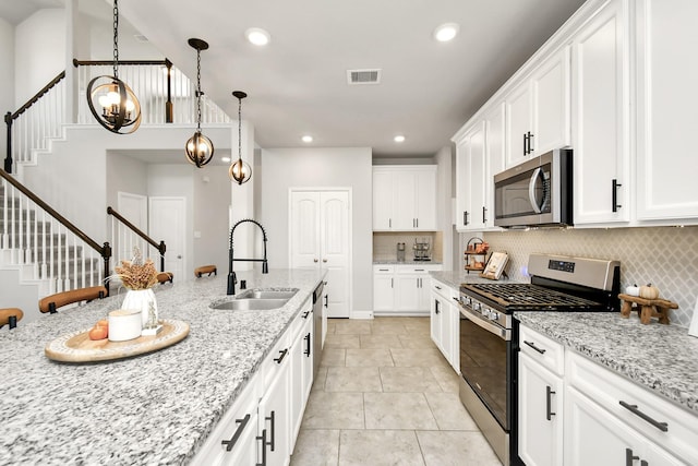 kitchen with sink, white cabinetry, tasteful backsplash, stainless steel appliances, and light stone countertops