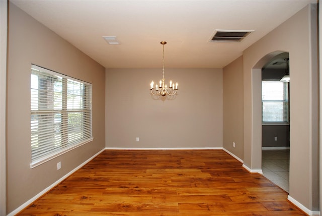 empty room featuring an inviting chandelier and hardwood / wood-style floors