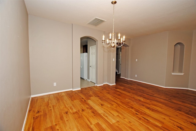 empty room featuring wood-type flooring and a chandelier