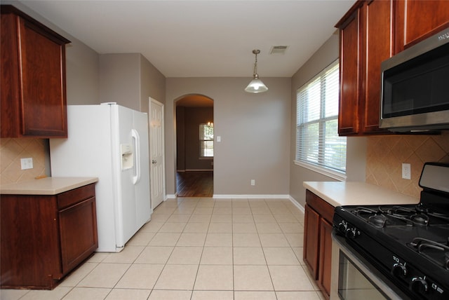 kitchen with backsplash, stainless steel appliances, hanging light fixtures, and light tile patterned flooring