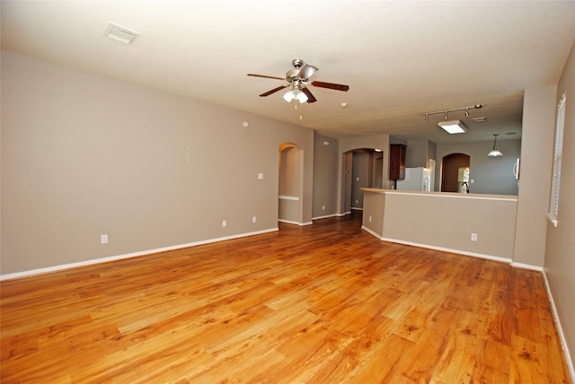 unfurnished living room with wood-type flooring, rail lighting, and ceiling fan