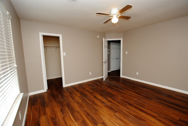 unfurnished bedroom featuring ceiling fan, a walk in closet, dark hardwood / wood-style floors, and a closet