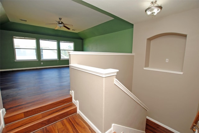 stairs with wood-type flooring, lofted ceiling, and ceiling fan