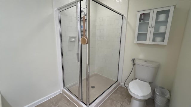 bathroom featuring a stall shower, tile patterned floors, toilet, and baseboards