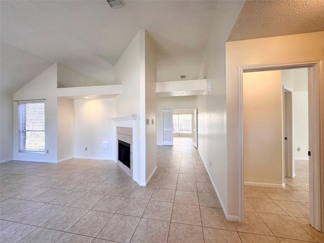 unfurnished living room featuring vaulted ceiling, light tile patterned flooring, a fireplace, and baseboards