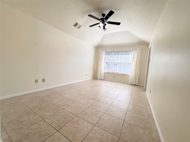 spare room featuring lofted ceiling, ceiling fan, light tile patterned floors, a textured ceiling, and visible vents