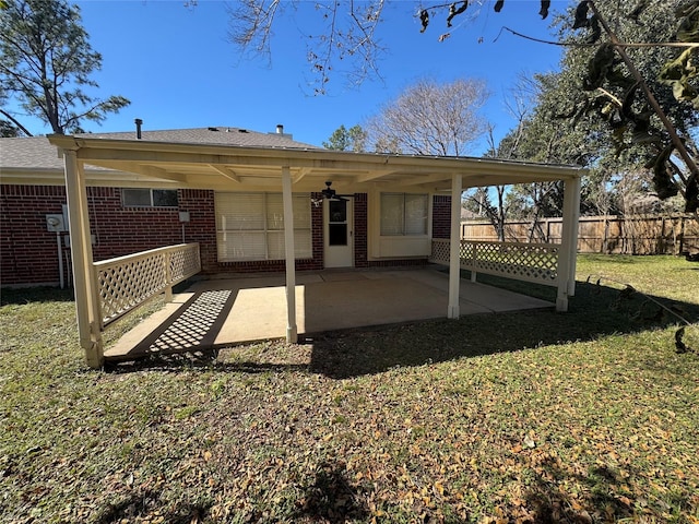 rear view of house with a patio area, a yard, fence, and brick siding