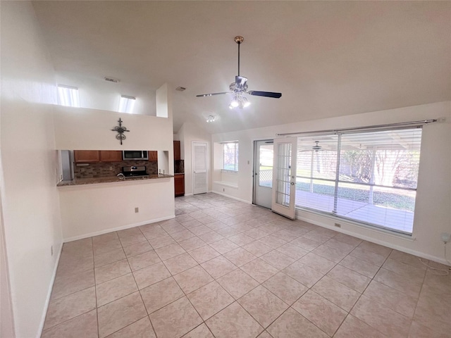 unfurnished living room with light tile patterned floors, high vaulted ceiling, visible vents, a ceiling fan, and baseboards