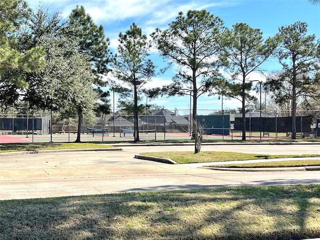 view of home's community with a tennis court and fence